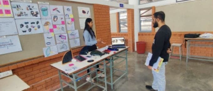 Akshay Katkade reviewing a student's product design presentation in a studio lined with sketches.